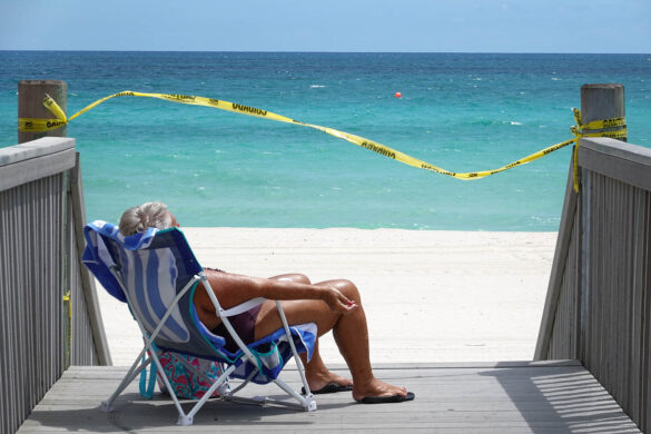 Una mujer se acerca lo más posible a la playa a lo largo de una costa cerrada en Hollywood, Florida, mientras más lugares turísticos están cerca para detener la propagación del coronavirus. Joe Raedle / Getty Images